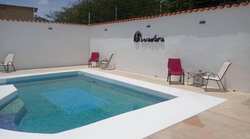 La MiraCasa Wadara的白色墙壁前的游泳池配有椅子和桌子