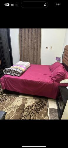 Manshīyat as Sādātشقة الزقازيق的一张位于带紫色床罩的房间内的床铺