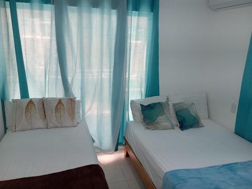 蓬塔卡纳Hostal Palmas De Punta Cana的配有蓝色窗帘的客房内的两张床