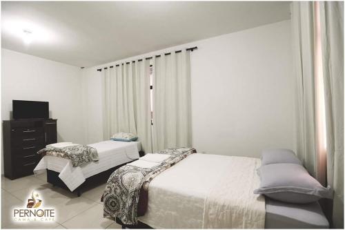 帕图布兰库Hotel pernoite的一间带两张床的卧室和一台电视