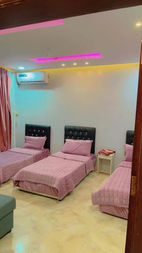 Yanbu Al Bahrشاليهات الساحل الغربي的配有粉红色床单的客房内的三张床