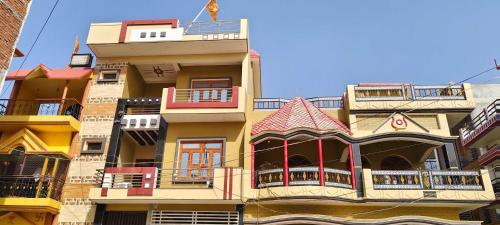 AyodhyaOYO Home Anandi Homestay的一座高大的黄色建筑,设有阳台