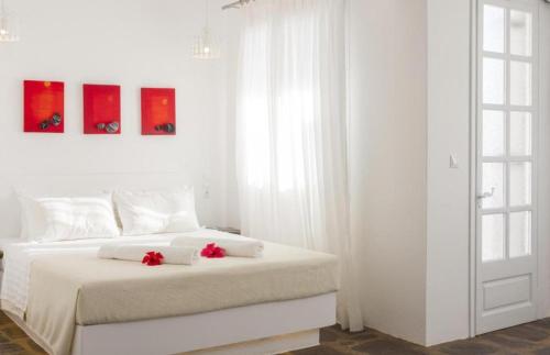 萨摩斯天蝎座公寓酒店及套房的白色卧室,床上有红色鲜花