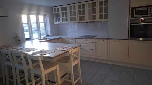 斯楚厄Hus med 10 soveplads的厨房配有白色橱柜和带凳子的桌子