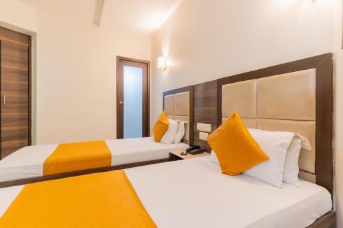 艾哈迈达巴德北京华侨大厦酒店的配有黄色枕头的酒店客房的两张床