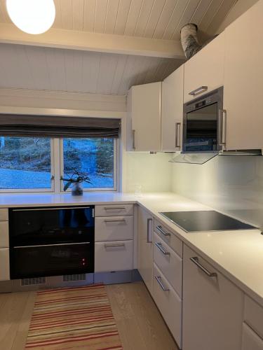 特罗姆瑟Håkøyveien 151, Tromsø的厨房配有白色橱柜和黑色用具