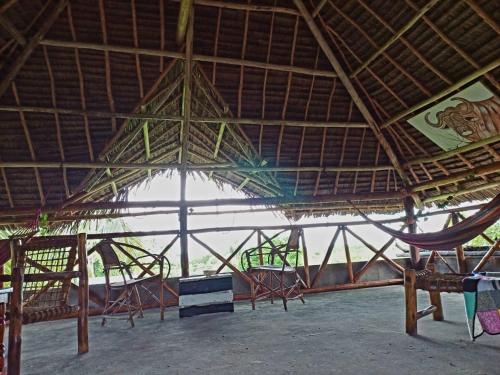 米查维Karibu Paradaizi的一座带稻草屋顶的大型建筑,配有椅子和吊床