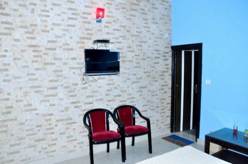 阿格拉Hotel Tourist Bar & Restaurant的砖墙上设有两把椅子和一台电视机