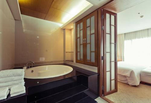 乌汶苏内大酒店和会议中心的带浴缸和床的浴室