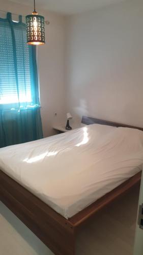 普里什蒂纳White Apartments的卧室内的一张床铺,配有蓝色窗帘和吊灯