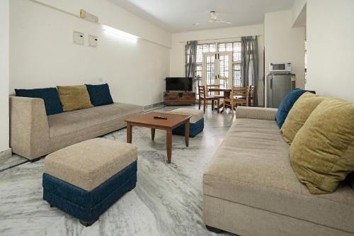 班加罗尔Aishwarya Mystic Apartotel的客厅配有两张沙发和一张桌子