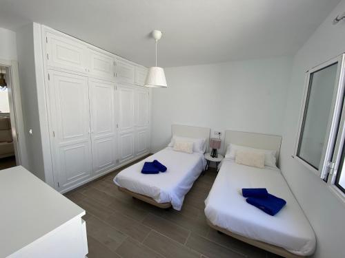 宏达海滩Playa Honda primera línea的配有白色墙壁和蓝色枕头的客房内的两张床