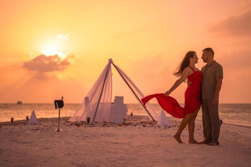北马累环礁可可博杜依酒店的日落时分一对夫妇站在海滩上