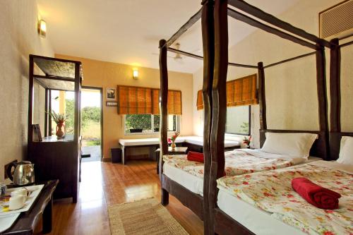 萨三吉尔Gir Birding Lodge的一间卧室设有两张天蓬床和一间浴室。