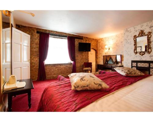 维斯贝希The Rose And Crown Hotel的一间卧室配有一张带红色床单的大床和窗户。