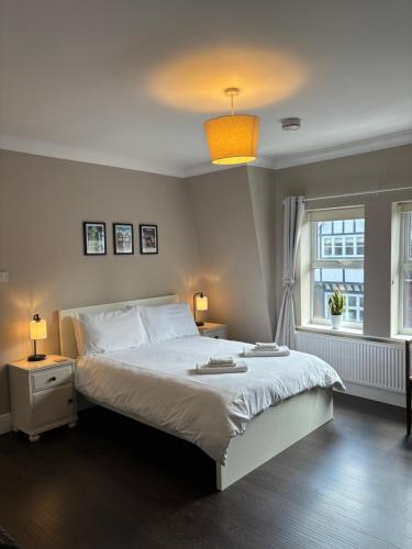 特灵Large West Side Room above G Grace & Son的卧室配有白色的床和窗户。