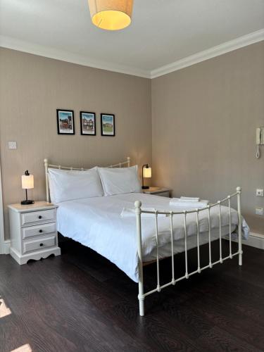特灵Large East Side Room above G Grace & Son的卧室配有一张白色床、两张桌子和两盏灯。