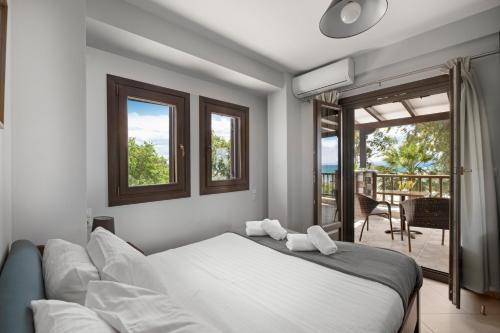 科罗皮Iakovakis Seaside Exclusive Apartments的一间带白色床的卧室和一个阳台