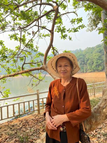 Ban Hin LomPhòng nghỉ Him Lam的戴帽子的老年妇女站在围栏旁边