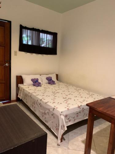 公主港LS花园别墅宾馆的一间卧室配有一张带紫色枕头的床和窗户。