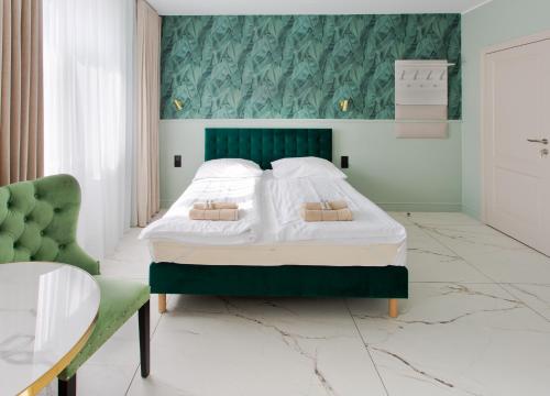 索波特Meduza Sopot的一间卧室配有一张大床和绿色床头板