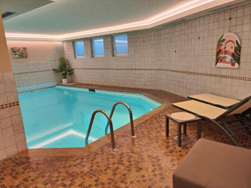 萨伦蒂诺Hotel Alpenblick的游泳池前设有桌子和长凳