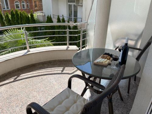 奥赫里德迪斯利维斯基别墅的阳台上的玻璃桌子和椅子,以及一瓶葡萄酒