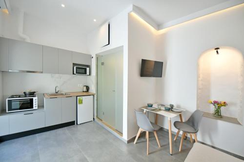 伊兹拉Douskos Citrus Apartments的厨房配有白色橱柜和桌椅