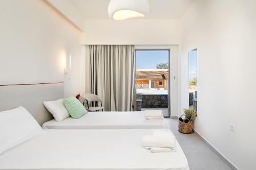 达西亚Little Corfu的一间白色卧室,配有两张床和窗户