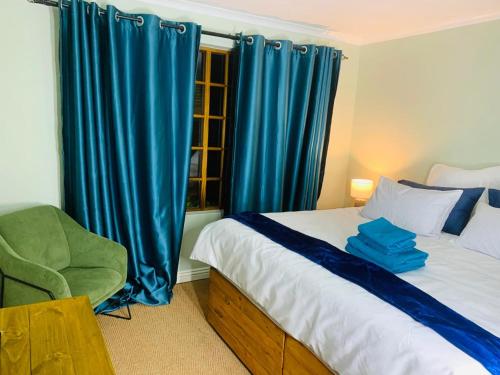 约翰内斯堡Afrikawisa@Rosebank的一间卧室配有一张带蓝色窗帘的床和一把椅子