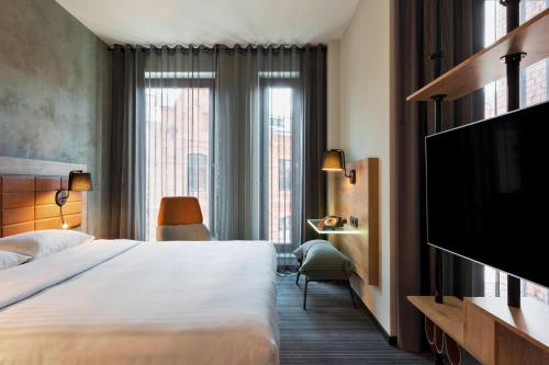 华沙Moxy Warsaw Praga的配有一张床和一台平面电视的酒店客房