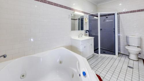 考拉布莱克奥特汽车旅馆的白色的浴室设有浴缸和卫生间。