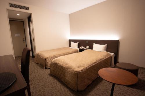 松山松山灿路都大饭店的酒店客房设有两张床和一张桌子。