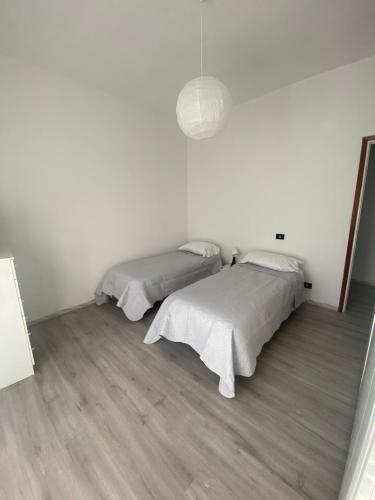 莱里奇Casa di Bianca的配有白色墙壁和木地板的客房内的两张床