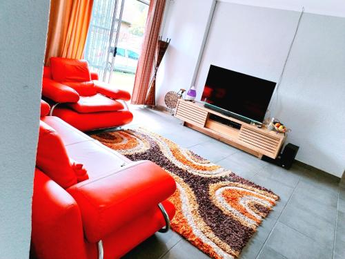 塞昆达Reutlwane Gardens house的客厅配有2把红色椅子和平面电视