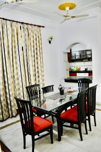 诺伊达Madhuraj Hotels的一间设有玻璃桌和椅子的用餐室