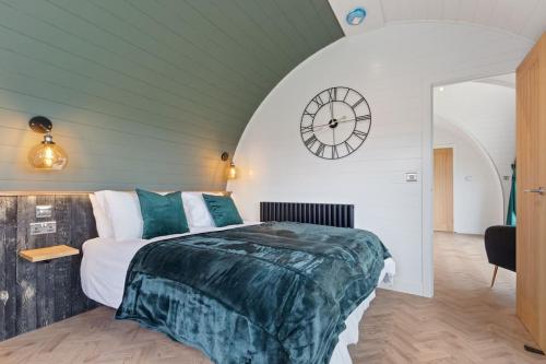 阿伦德尔Choller Lodges - The Barn House With Hot Tub的卧室配有一张床,墙上挂着一个钟