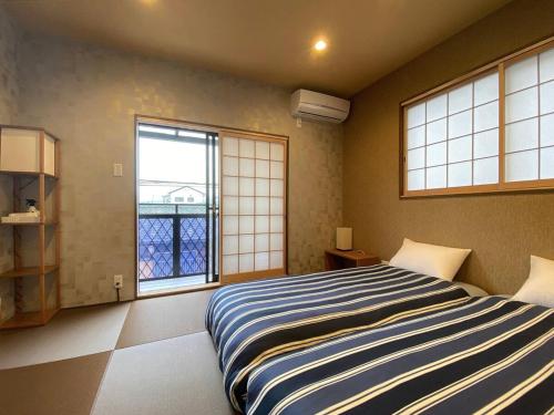 泉佐野My Home Inn Izumisano的一间卧室设有一张大床和两个窗户。
