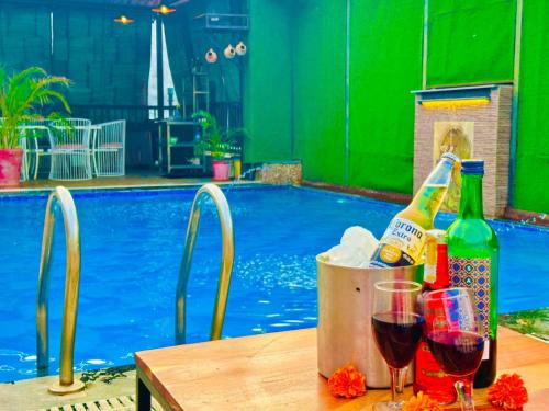 阿姆利则Hamilton Hotel & Resort, Near Golden Temple Parking Amritsar的游泳池旁配有酒瓶和玻璃杯的桌子