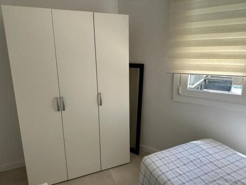 塞古德卡拉斐Playa y confort en Segur de Calafell的卧室配有白色橱柜、床和窗户。