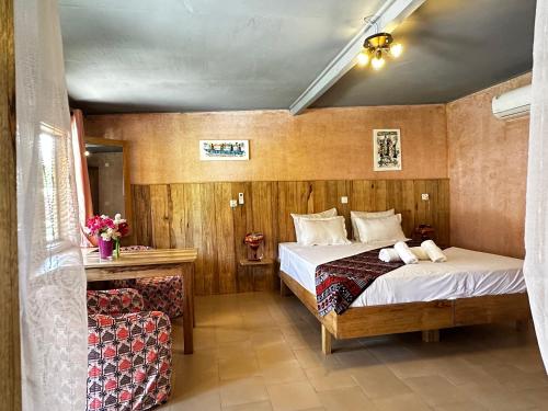 MbodièneMariama Lodge的配有一张床和一把椅子的酒店客房