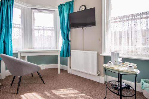伦敦金斯阿姆斯住宿加早餐旅馆的一间带椅子、桌子和电视的房间