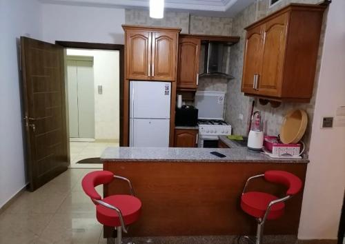 Umm Uthainahشقه في عبدون للإيجار的厨房配有柜台和2把红色椅子