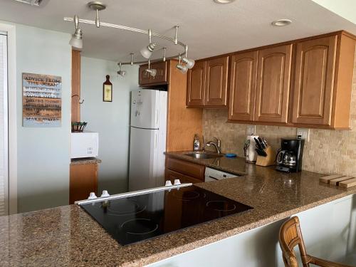 新士麦那海滩Pelican Condominium的厨房配有木制橱柜和黑色台面