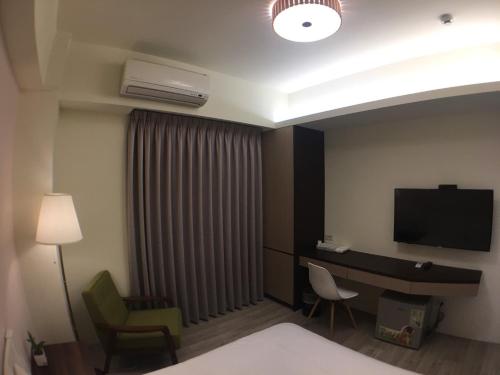 台中市舒悦文旅 台中逢甲店 的酒店客房配有一张床、一张书桌和一台电视。