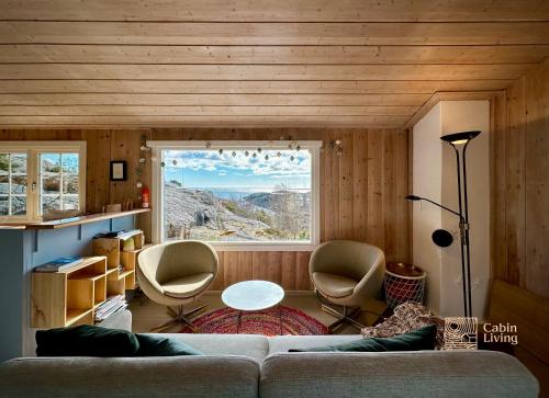 利勒桑Idyllic Cabin in Lillesand fantastic ocean view的带沙发和椅子的客厅以及窗户。