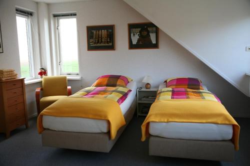 Zuid-Beijerland科伦代克住宿加早餐旅馆的一间卧室配有两张带黄色和色彩缤纷的毯子的床