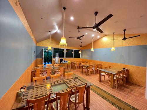 马西尼古蒂The Midway Jungle Resort的餐厅配有木桌、椅子和吊扇