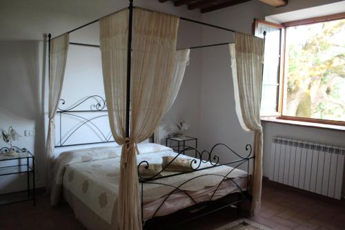 BoccheggianoAgriturismo La Quercia的一间卧室设有天蓬床和窗户。