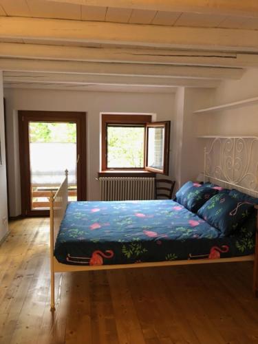 AttimisCasa Borc di Nelle的一间卧室配有一张蓝色棉被和两个窗户。